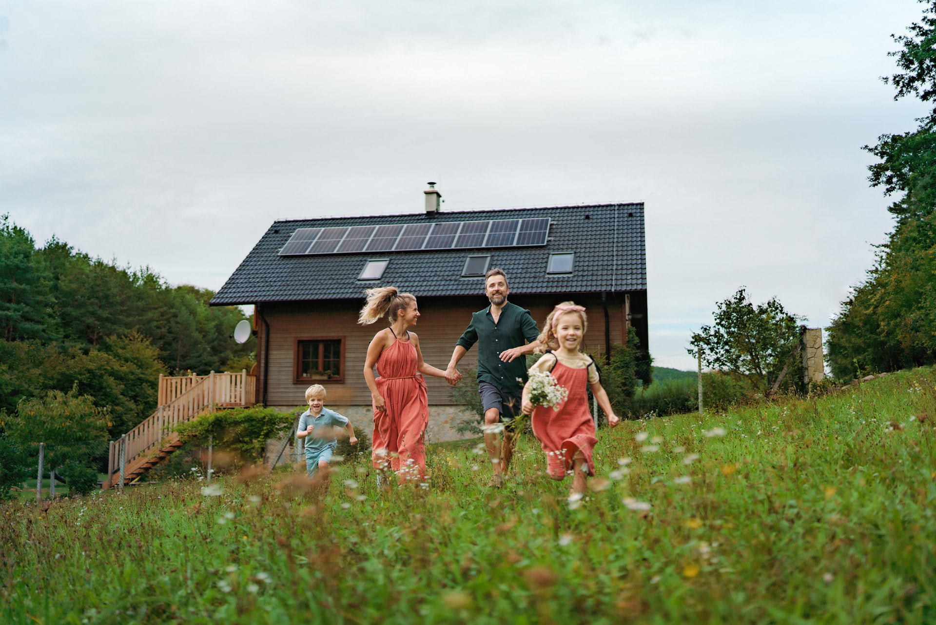 Famille courant devant une maison équipée de panneaux solaires
